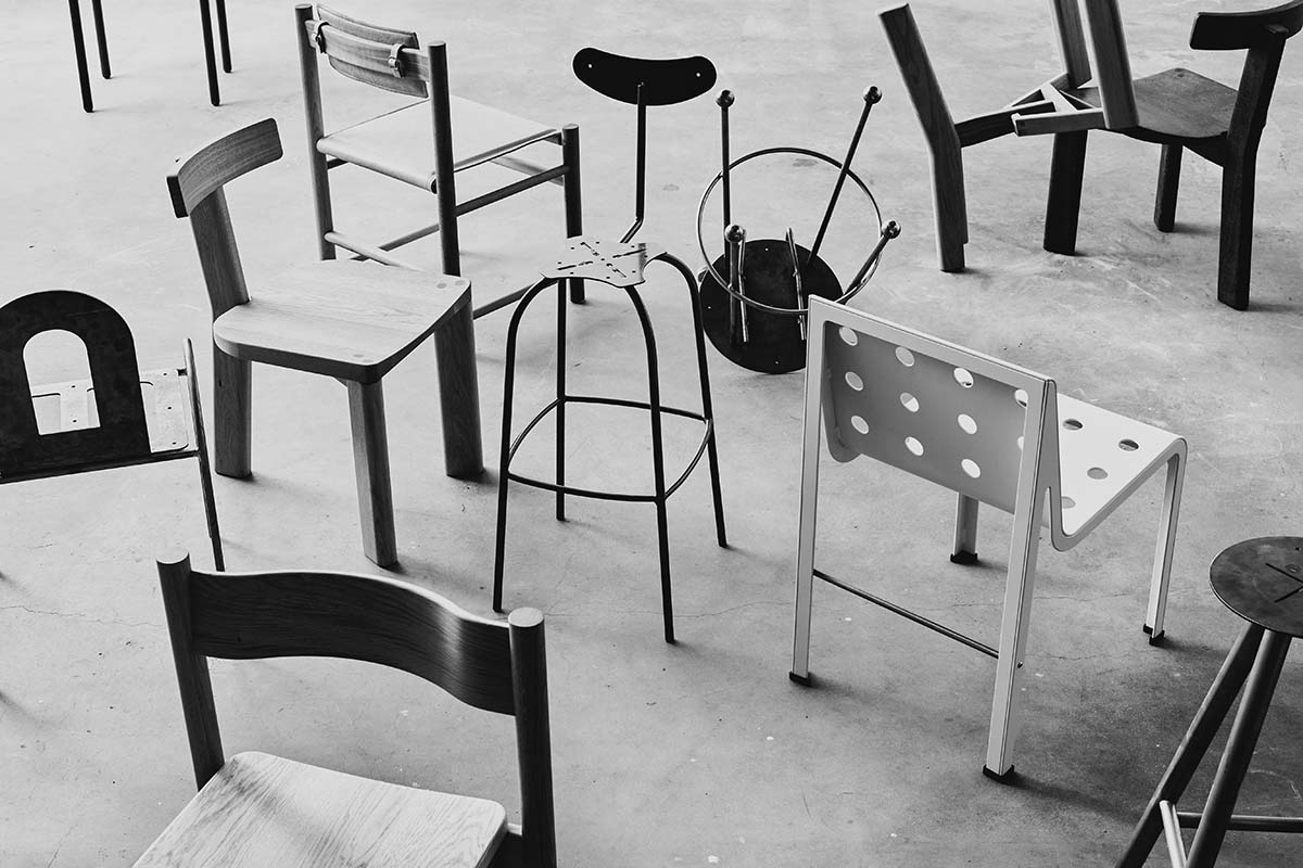 A roughly finished showroom showcasing aluminium furniture including stools, tables, chairs, and a picnic bench. The Remington Matters logo is rendered in steel and attached to the back wall.